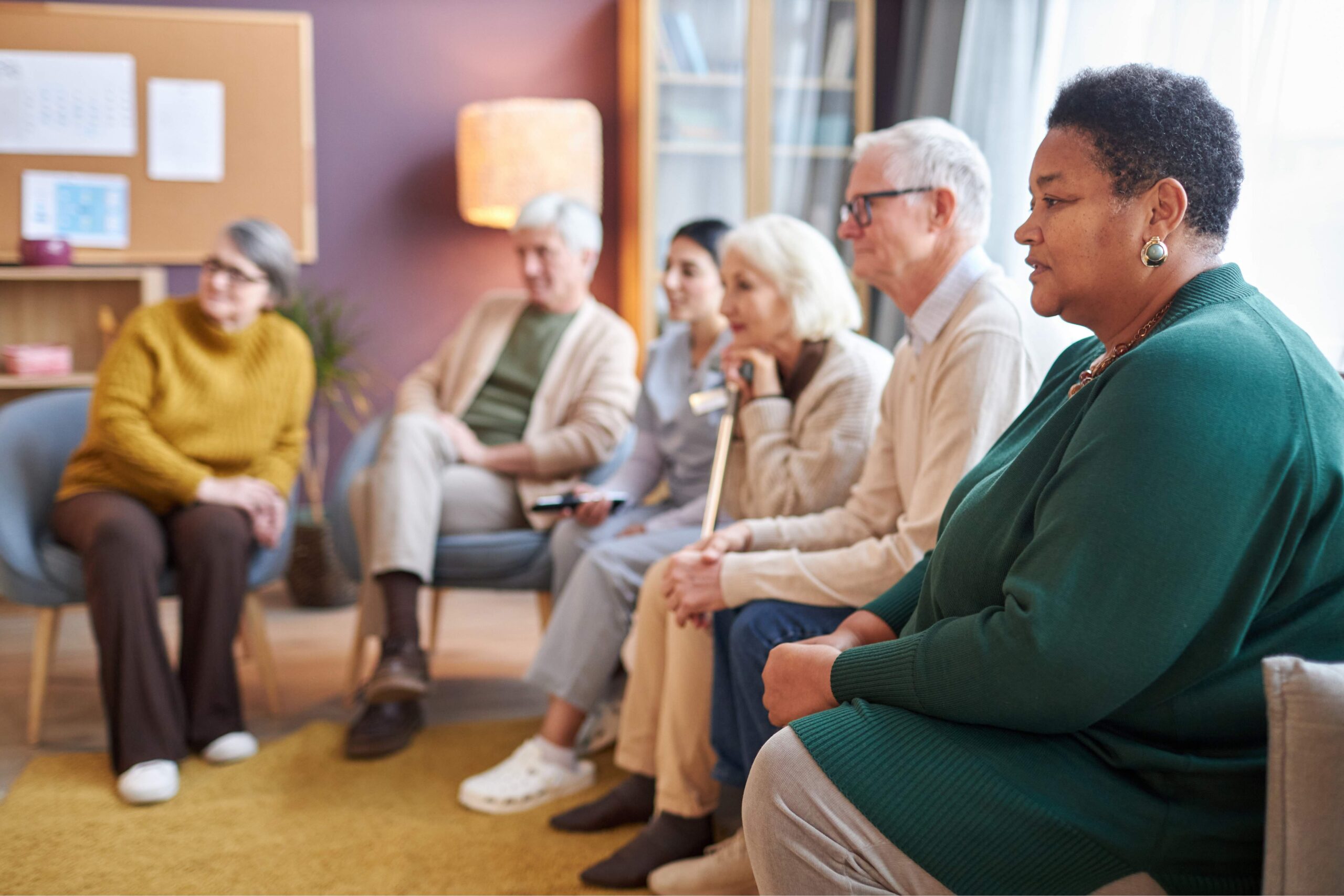 Side view at multiethnic group of elderly people watching TV sitting in row together in retirement home